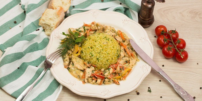 Куриное фрикасе с овощами и отварным рисом на тарелке